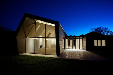 Réalisation d'une façade de maison noire design en bois de taille moyenne et de plain-pied.