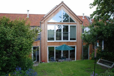 Cette image montre une façade de maison blanche rustique en bois de taille moyenne et à un étage avec un toit à deux pans et un toit en tuile.