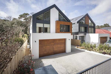 Expansive and white modern house exterior in Dorset with three floors, mixed cladding and a mansard roof.