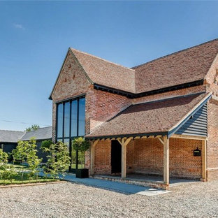 This is an example of a large and red contemporary brick detached house in Hertfordshire with three floors.