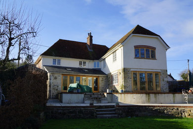 This is an example of a beige classic house exterior in Wiltshire with stone cladding and a hip roof.