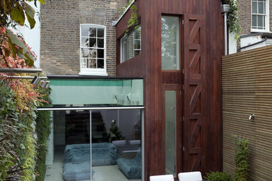 Medium sized and white contemporary house exterior in London with three floors, wood cladding and a mansard roof.
