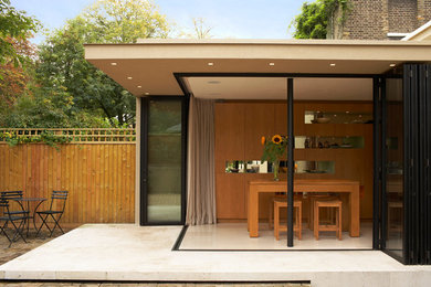 Photo of a medium sized and beige modern bungalow render house exterior in London.