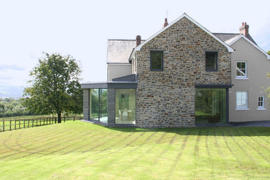 Cette photo montre une grande façade de maison éclectique en pierre à un étage.