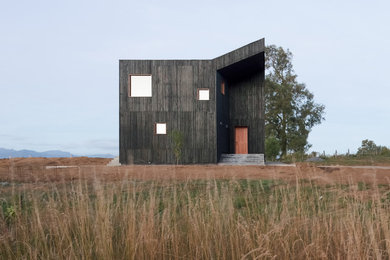 Modelo de fachada de casa negra minimalista grande de dos plantas con revestimiento de madera, tejado de metal y tejado plano