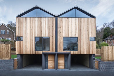 Idée de décoration pour une façade de maison marron design en bois avec un toit à deux pans.