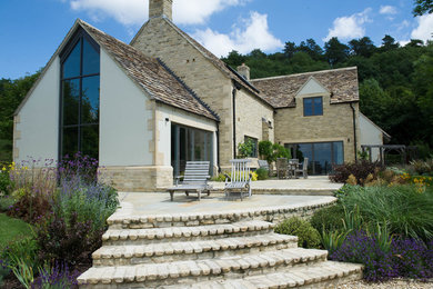 Foto de fachada de casa beige de estilo de casa de campo grande de dos plantas con revestimientos combinados y tejado a dos aguas