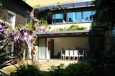 Diseño de fachada blanca mediterránea de tamaño medio de dos plantas con revestimiento de ladrillo