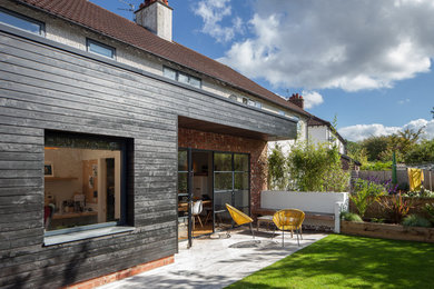 Black contemporary bungalow semi-detached house in Manchester with wood cladding and a flat roof.