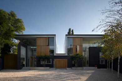 Diseño de fachada de casa negra contemporánea grande de tres plantas con revestimiento de ladrillo, tejado plano y tejado de metal