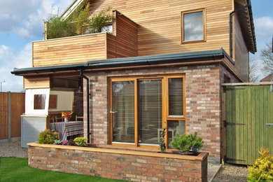 This is an example of a small contemporary two floor house exterior in Other with mixed cladding and a pitched roof.