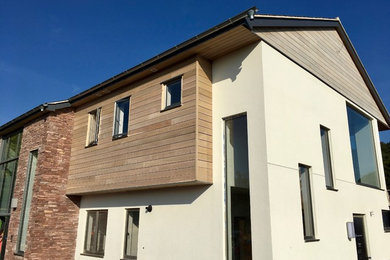 Medium sized and multi-coloured contemporary two floor detached house in Cheshire with mixed cladding, a pitched roof and a tiled roof.