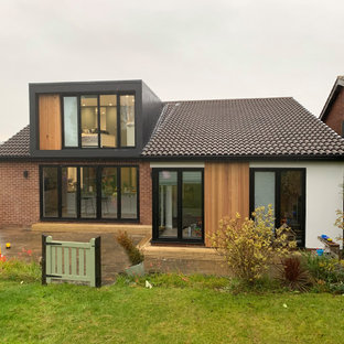 Bild på ett litet funkis svart hus, med två våningar, stuckatur och platt tak