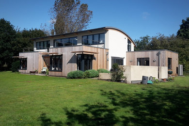 Medium sized and white contemporary two floor detached house in Other with wood cladding and a metal roof.