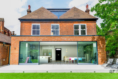 Inspiration for a red contemporary brick house exterior in London with three floors and a hip roof.