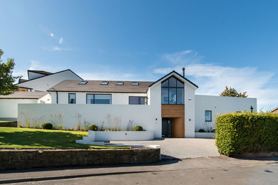This is an example of a white contemporary render house exterior in Other with three floors, a pitched roof and a tiled roof.