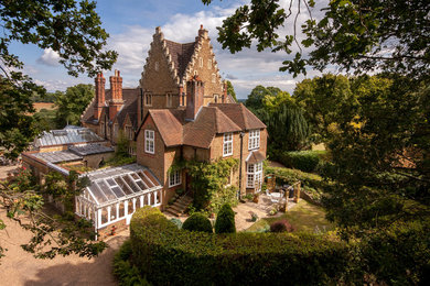 Inspiration for a traditional brick house exterior in Surrey with three floors.
