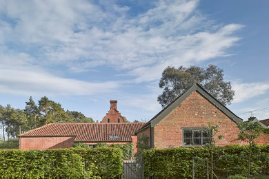 Aménagement d'une petite façade de maison rouge contemporaine en brique de plain-pied avec un toit à deux pans.