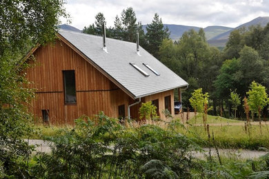 Ejemplo de fachada marrón escandinava pequeña de dos plantas con revestimiento de madera y tejado a dos aguas