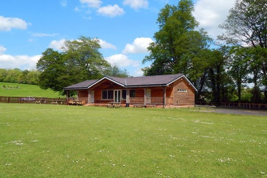 Photo of a medium sized country bungalow house exterior in Dorset with wood cladding and a pitched roof.