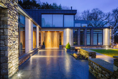 Photo of a large and black modern two floor house exterior in Other with stone cladding and a flat roof.