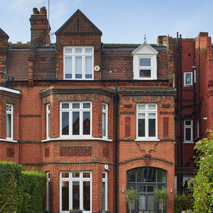 This is an example of a red traditional brick terraced house in London with three floors and a pitched roof.