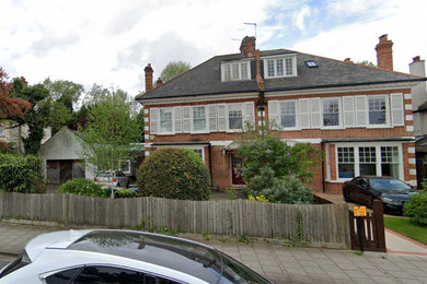 Photo of a large and red contemporary house exterior in London with three floors and a shingle roof.