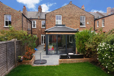 This is an example of a red traditional two floor brick terraced house in London with a pitched roof and a tiled roof.