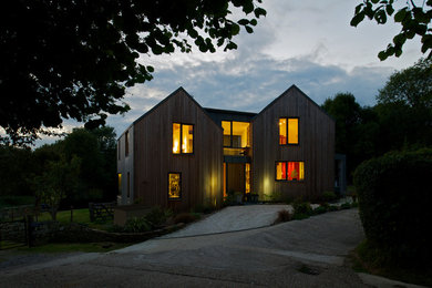 Réalisation d'une grande façade de maison marron design en bois à un étage avec un toit à deux pans.