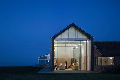 Diseño de fachada de casa actual grande de una planta con revestimiento de ladrillo, tejado a dos aguas y tejado de teja de barro