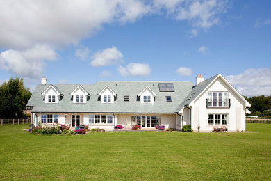 This is an example of a large and white traditional two floor house exterior in Other with a pitched roof.