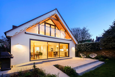Diseño de fachada de casa blanca contemporánea grande de dos plantas con revestimiento de estuco, tejado a dos aguas y tejado de teja de barro