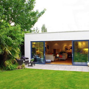Expansive and white modern one floor glass house exterior in London with a flat roof.
