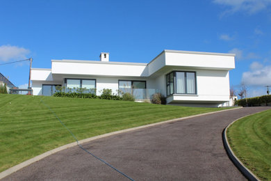 Bild på ett funkis vitt hus, med platt tak