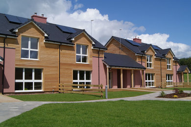 Imagen de fachada de casa bifamiliar multicolor campestre de tamaño medio de dos plantas con revestimiento de madera, tejado a dos aguas y tejado de teja de barro