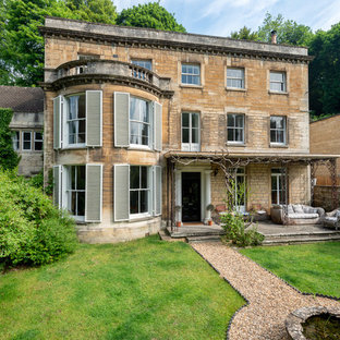 This is an example of a large and beige victorian two floor detached house in Gloucestershire with stone cladding, a tiled roof and a flat roof.