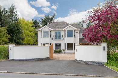 Modelo de fachada de casa beige minimalista grande de tres plantas con revestimiento de estuco y tejado a cuatro aguas