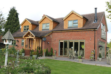 Photo of a large and red rural two floor detached house in Hampshire with wood cladding, a pitched roof and a tiled roof.