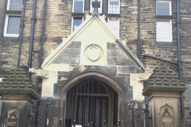 This is an example of a medium sized and beige traditional house exterior in Other with stone cladding.