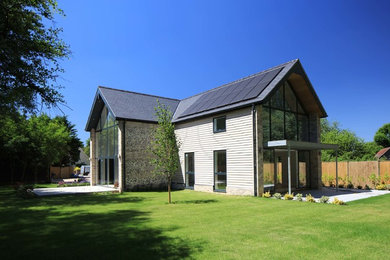 Imagen de fachada de casa beige contemporánea grande de dos plantas con revestimiento de piedra, tejado a dos aguas y tejado de teja de barro
