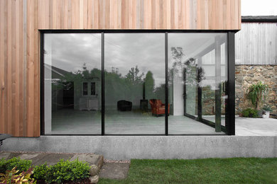 Inspiration pour une façade de maison marron en bois de taille moyenne et de plain-pied avec un toit plat.