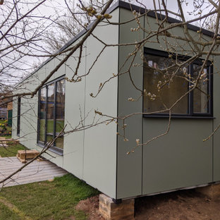 Modelo de fachada verde, contemporánea, pequeña, de una planta, con revestimientos combinados, tejado plano y tejado de varios materiales