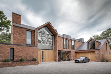 Photo of a large and red contemporary brick detached house in Manchester with three floors, a pitched roof and a tiled roof.