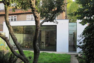 Inspiration for a large and white contemporary render house exterior in London with three floors and a flat roof.