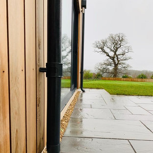 Immagine della facciata di una casa a schiera nera contemporanea a due piani di medie dimensioni con rivestimento in legno, tetto piano e copertura verde