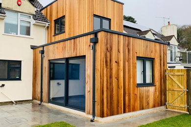 Idee per la facciata di una casa a schiera nera contemporanea a due piani di medie dimensioni con rivestimento in legno, tetto piano e copertura verde