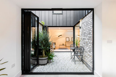 Large and black contemporary two floor terraced house in London with metal cladding, a pitched roof and a metal roof.