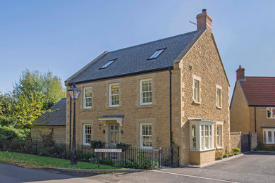This is an example of a medium sized and beige classic detached house with stone cladding, a pitched roof, a tiled roof and three floors.