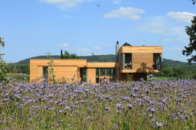Photo of a brown contemporary house exterior in Other with wood cladding.