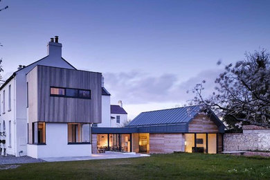 Inspiration for an expansive and white contemporary two floor house exterior in Dublin with wood cladding and a pitched roof.